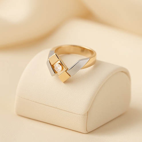 Bague élégante pour femme aux formes géométriques, composée d’un anneau doré, de détails argentés et d’une pierre lumineuse, présentée sur un support crème.